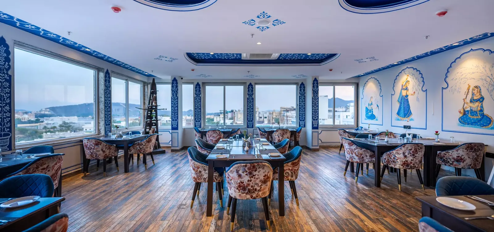 Indoor rooftop dining hall with blue Mewar ceiling and panoramic windows